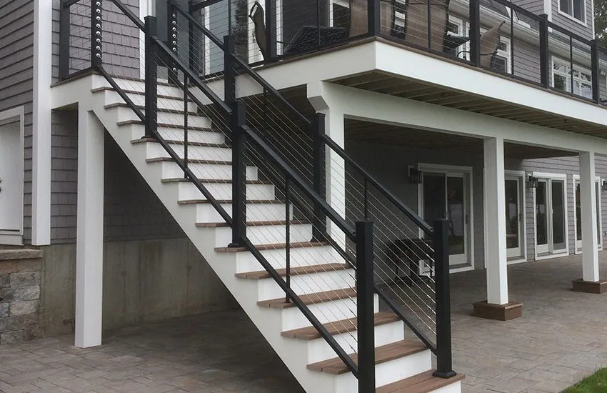 Deck stairs with wood treads and black cable railing system leading to covered patio area