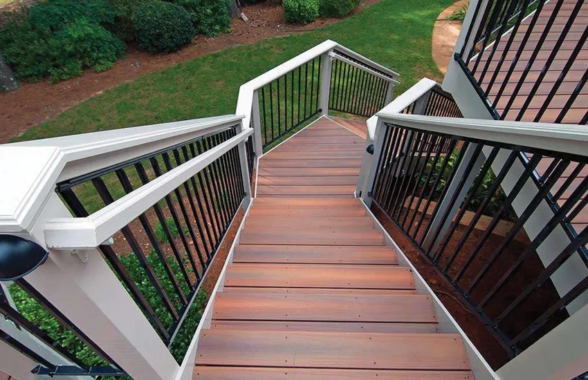 Wide deck staircase with platform landing overlooking landscaped backyard