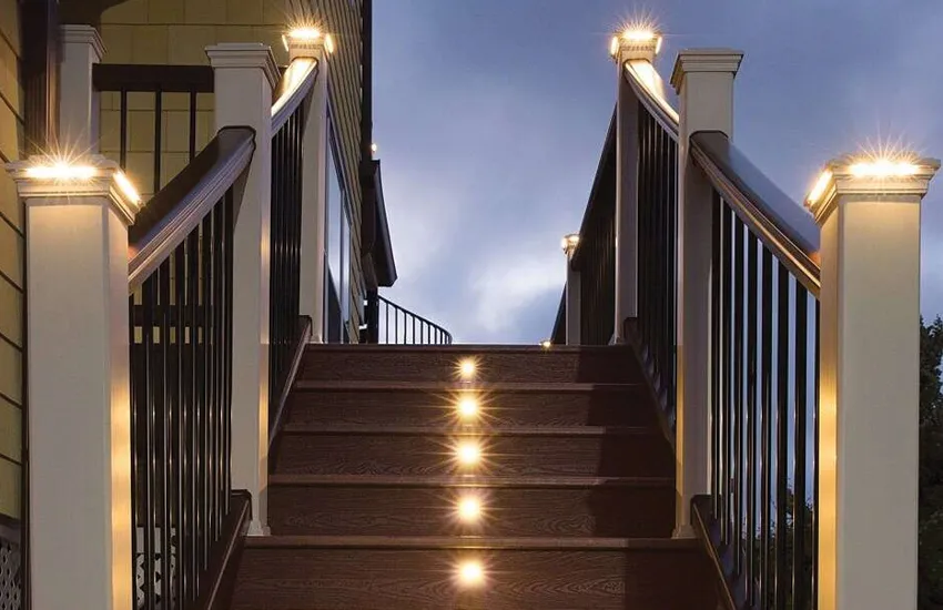 Composite deck stairs with post cap lights and stair riser lights creating warm evening ambiance