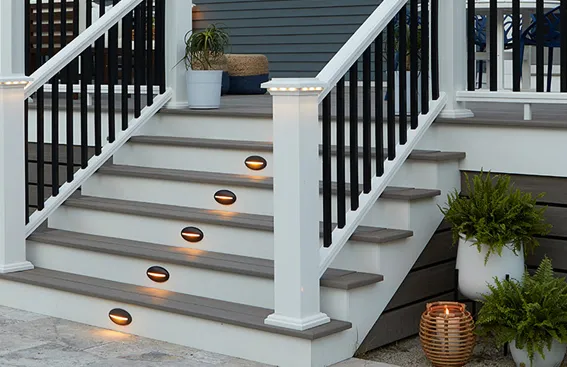 Gray composite deck steps with copper-colored recessed riser lights and white railing